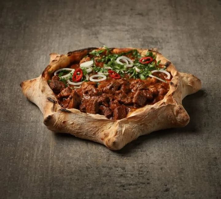 Brotschiffchen mit Rindereintopf, Zwiebeln, Chili und frischen Kräutern